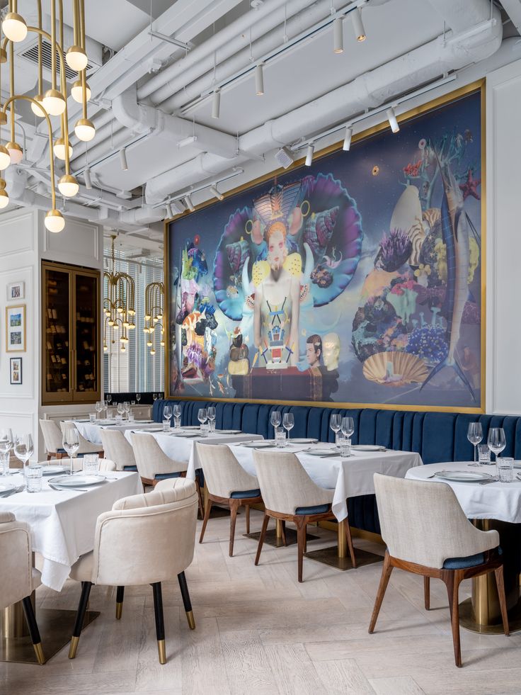 the dining room is set up with white tablecloths and chairs, along with a large painting on the wall