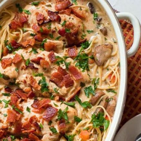 a casserole dish with chicken, bacon and pasta in it on a table