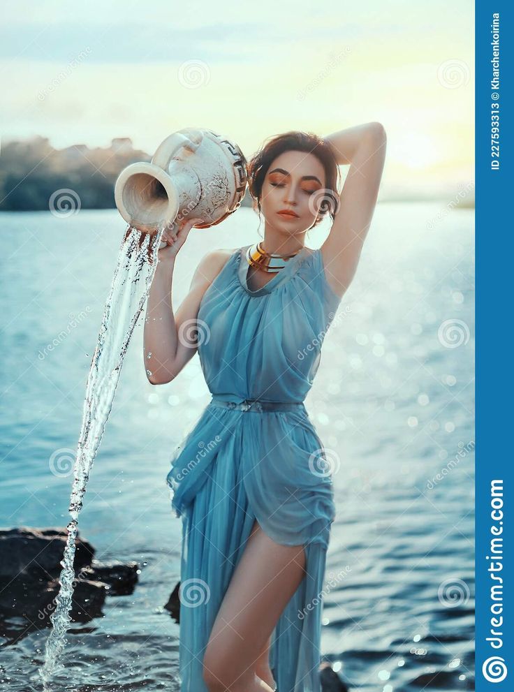 a woman in a blue dress is standing by the water