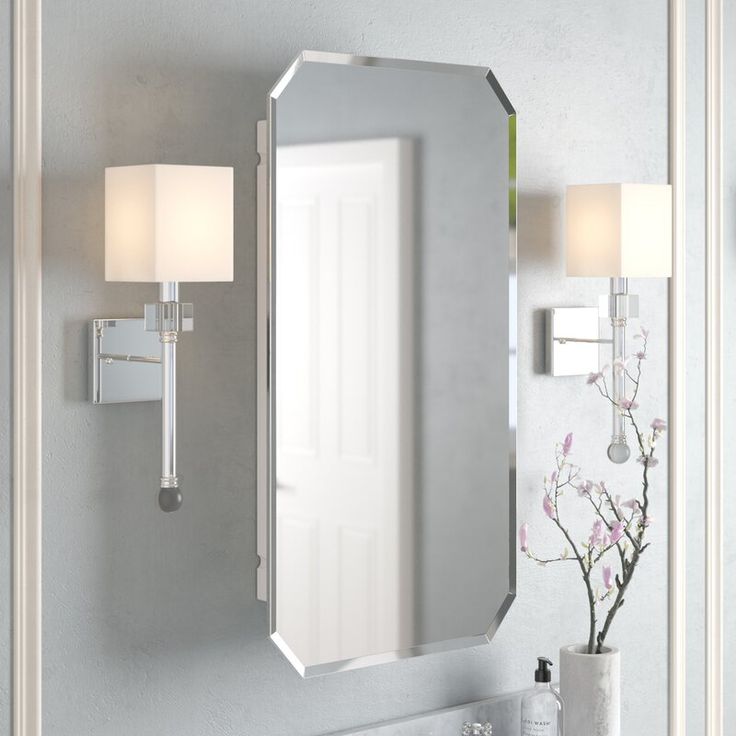 a bathroom vanity with a mirror and two lights on the wall next to a vase