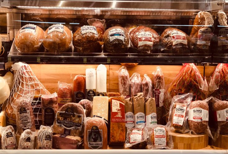 an assortment of meats and cheeses on display in a deli or bakery