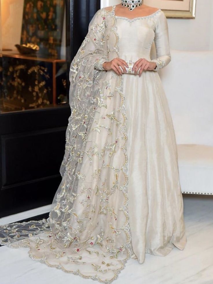 a woman in a white gown standing next to a chair