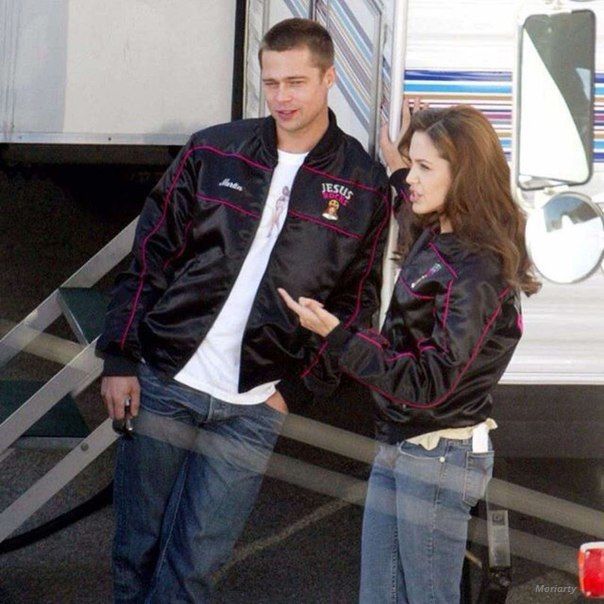 a man and woman standing next to each other in front of a white truck with the door open