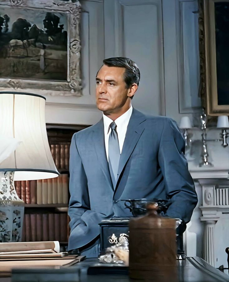 a man in a suit and tie sitting at a desk with a lamp on it