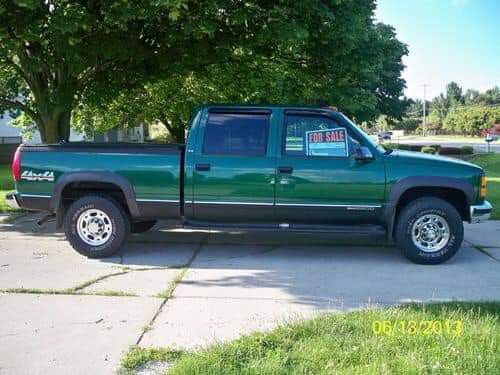 a green pick up truck parked in front of a tree