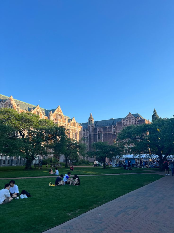 people sitting on the grass in front of a building