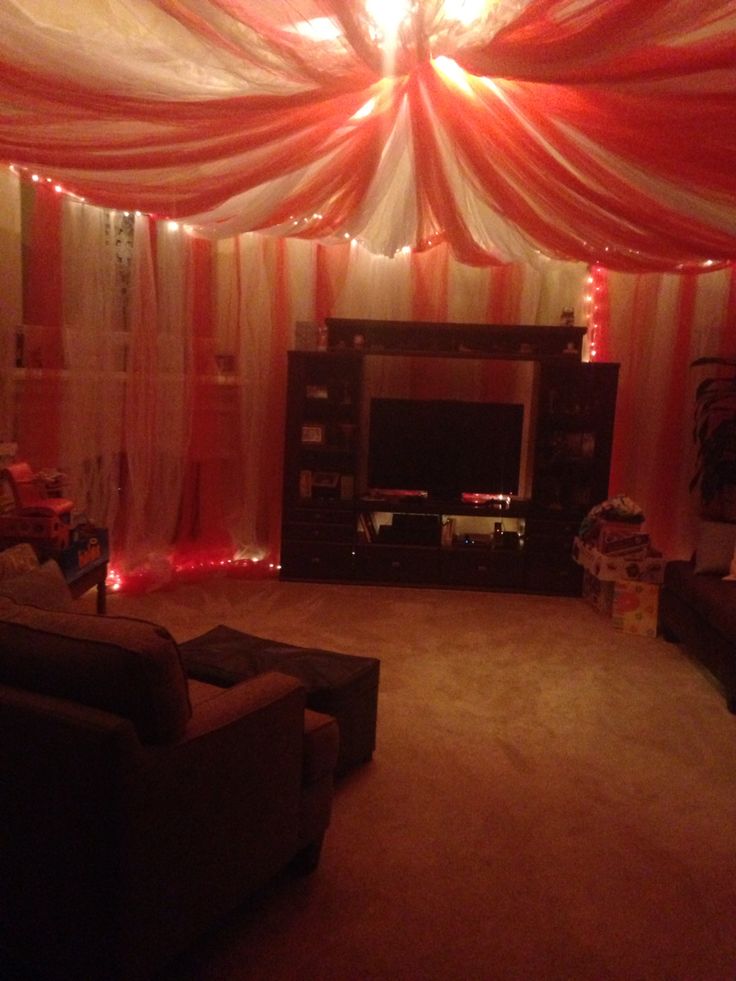 the living room is decorated with red and white drapes, lights, and furniture