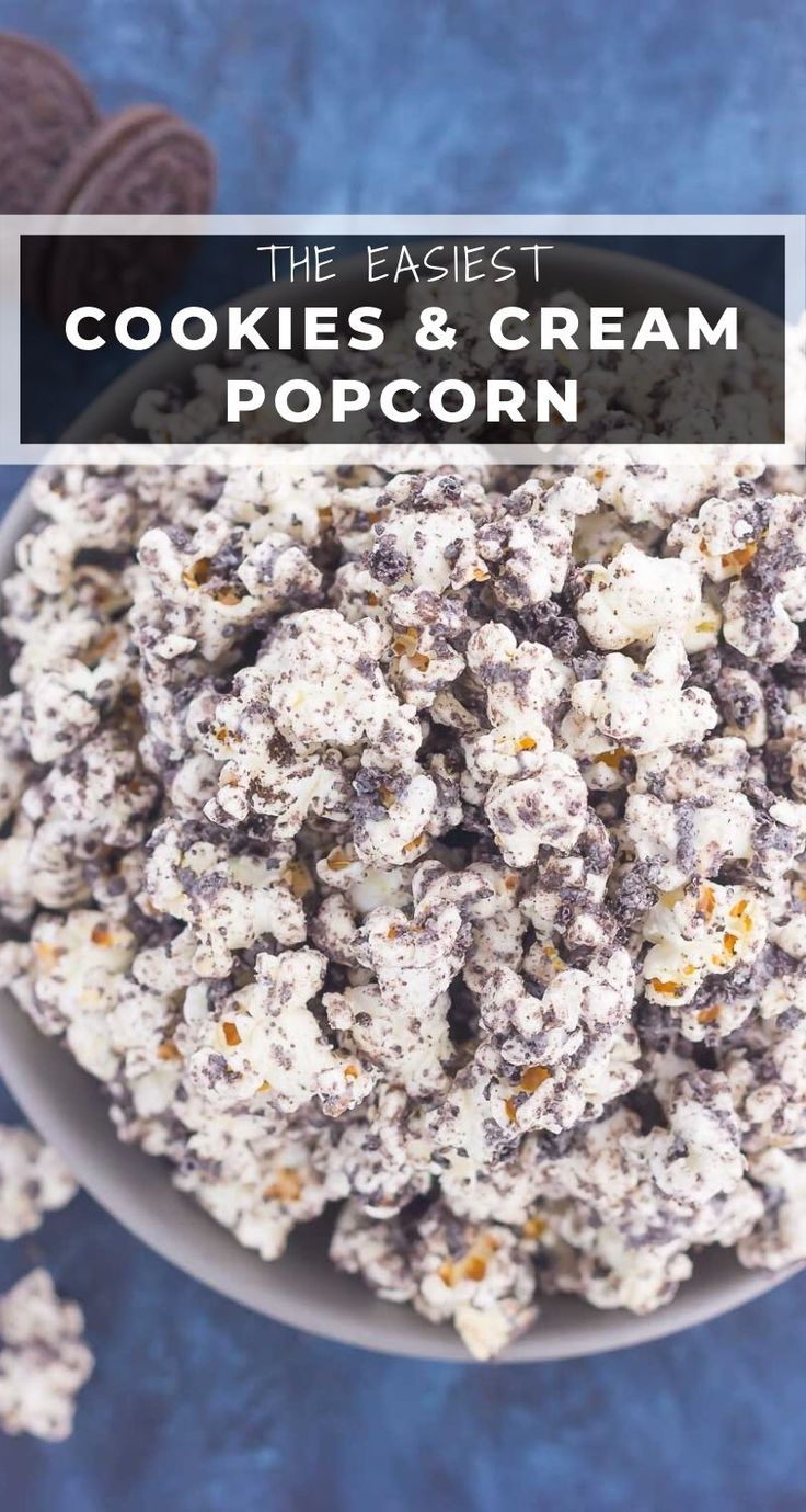 a bowl filled with cookies and cream popcorn on top of a blue tablecloth next to some cookies