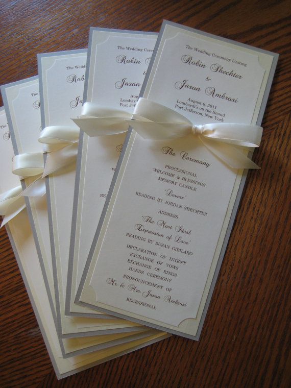 four wedding cards with bows on them sitting on a wooden table next to each other