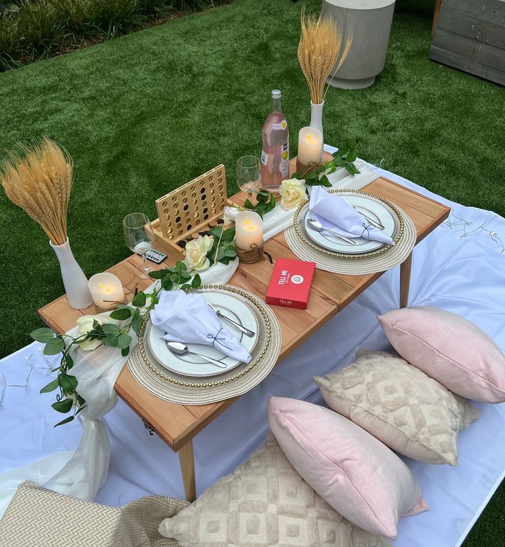 a table set up with plates and place settings for an outdoor dinner on the grass