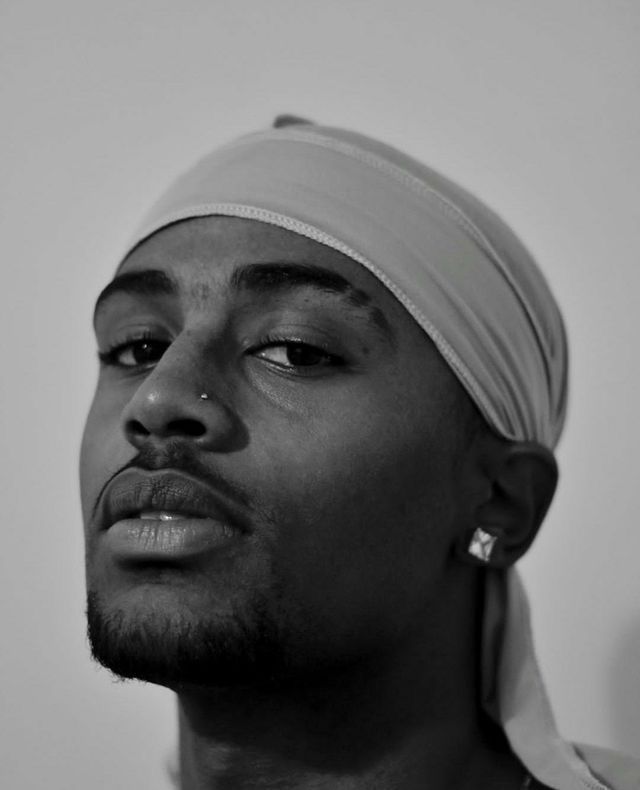 a man with a turban on his head looking off to the side in black and white