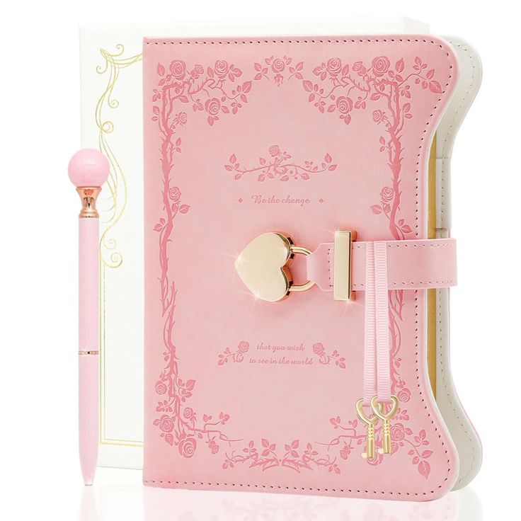 a pink notebook with a gold ring on it and a pen in front of it