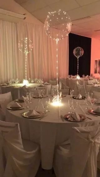 a banquet room set up with white linens and balloons