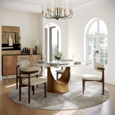 a dining room table with chairs and a chandelier hanging from the ceiling in front of two arched windows