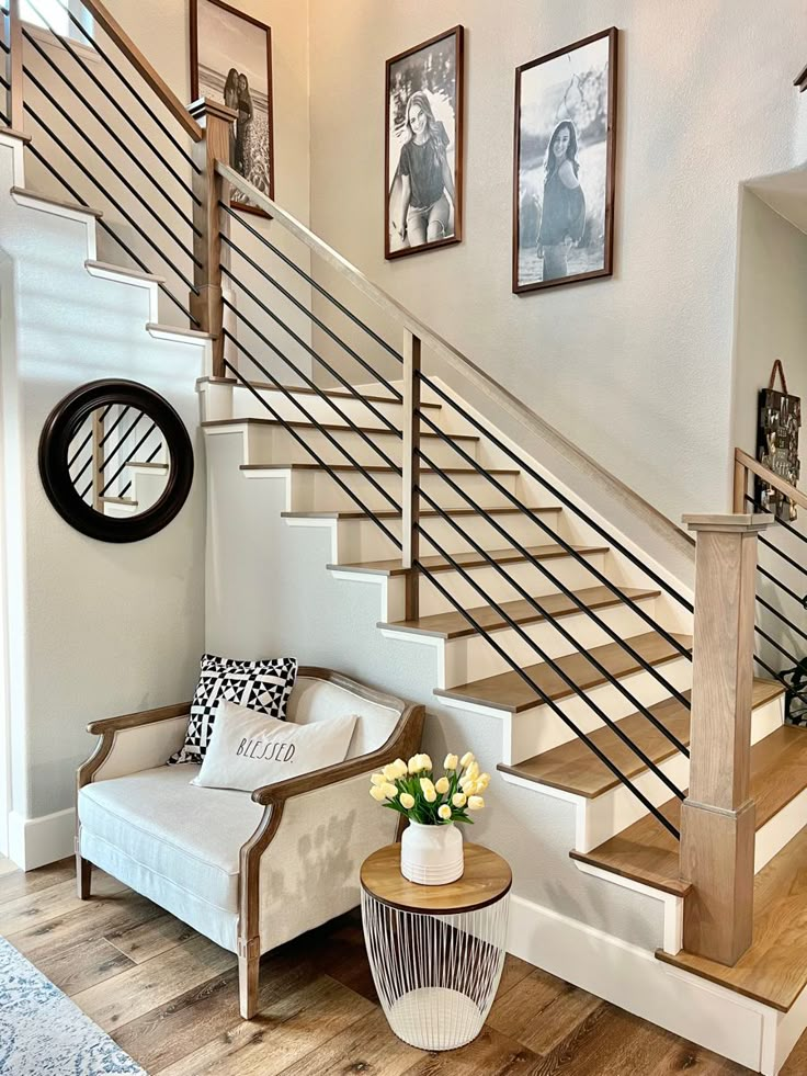 a white couch sitting under a stair case next to a wooden table with flowers on it