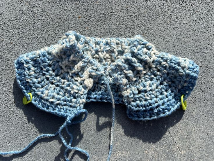 a blue and white knitted hat laying on top of a gray floor next to a string