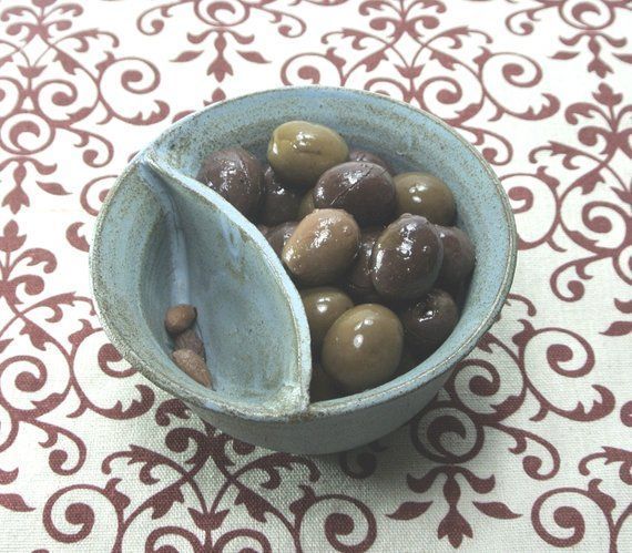 a bowl filled with olives sitting on top of a table