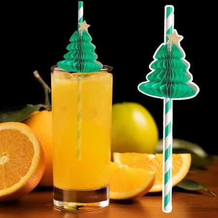 an orange drink with two green christmas trees on top, and some sliced oranges in the background