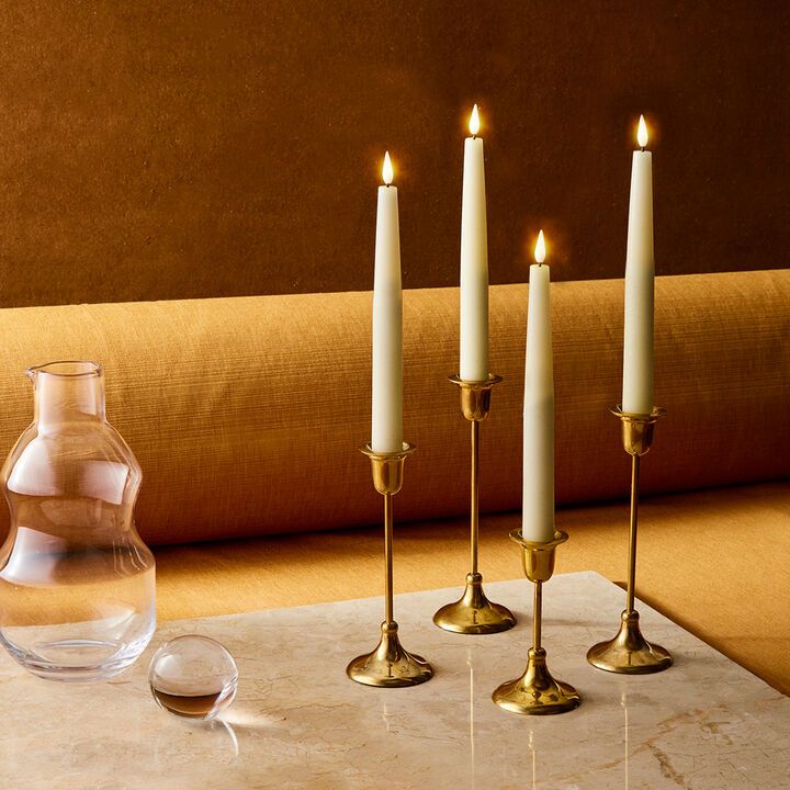 four candles on a table next to a vase