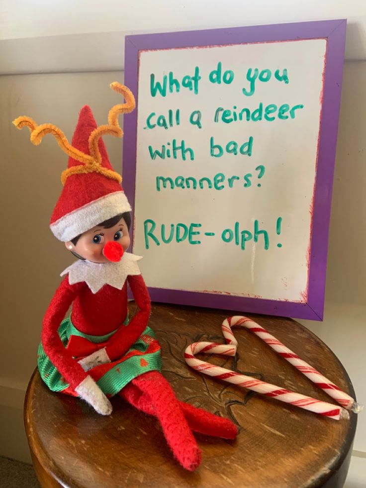 an elf sitting on top of a wooden table next to a sign that says, what do you call a reminder with bad manners? rude - oph