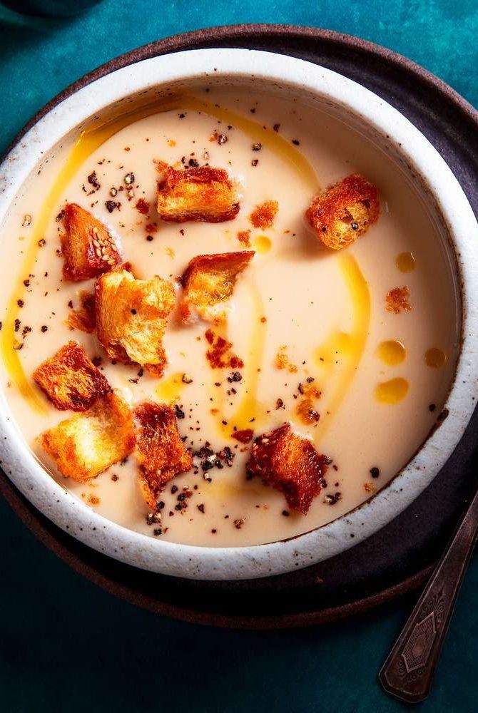 a bowl filled with soup and croutons on top of a blue table cloth