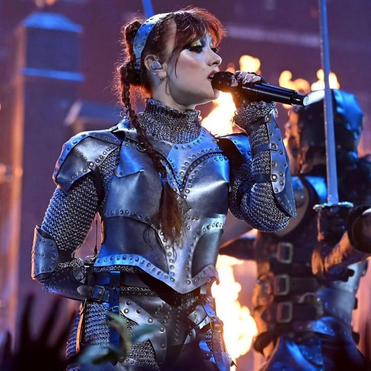 a woman in armor singing into a microphone