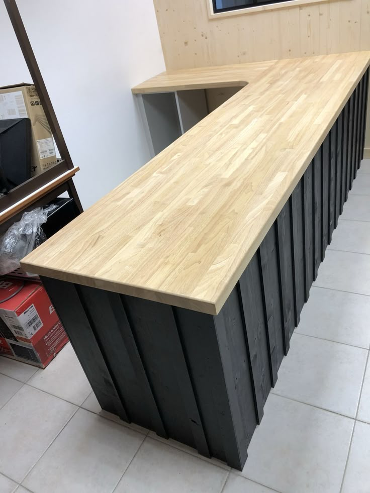 a counter top made out of black metal and wooden planks in a room with tile flooring