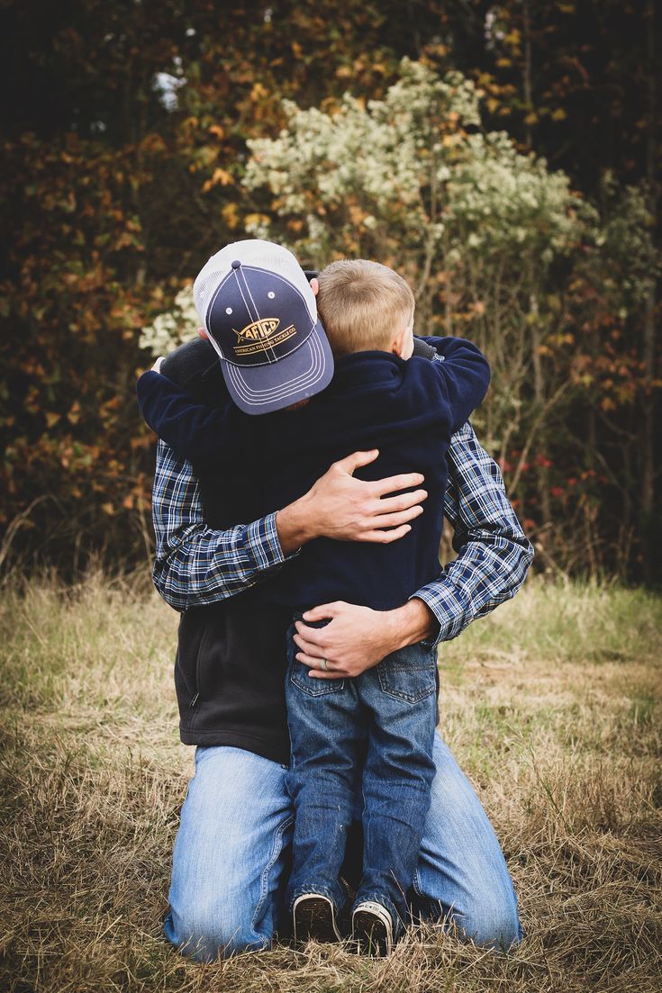 a father and son hugging each other in the grass