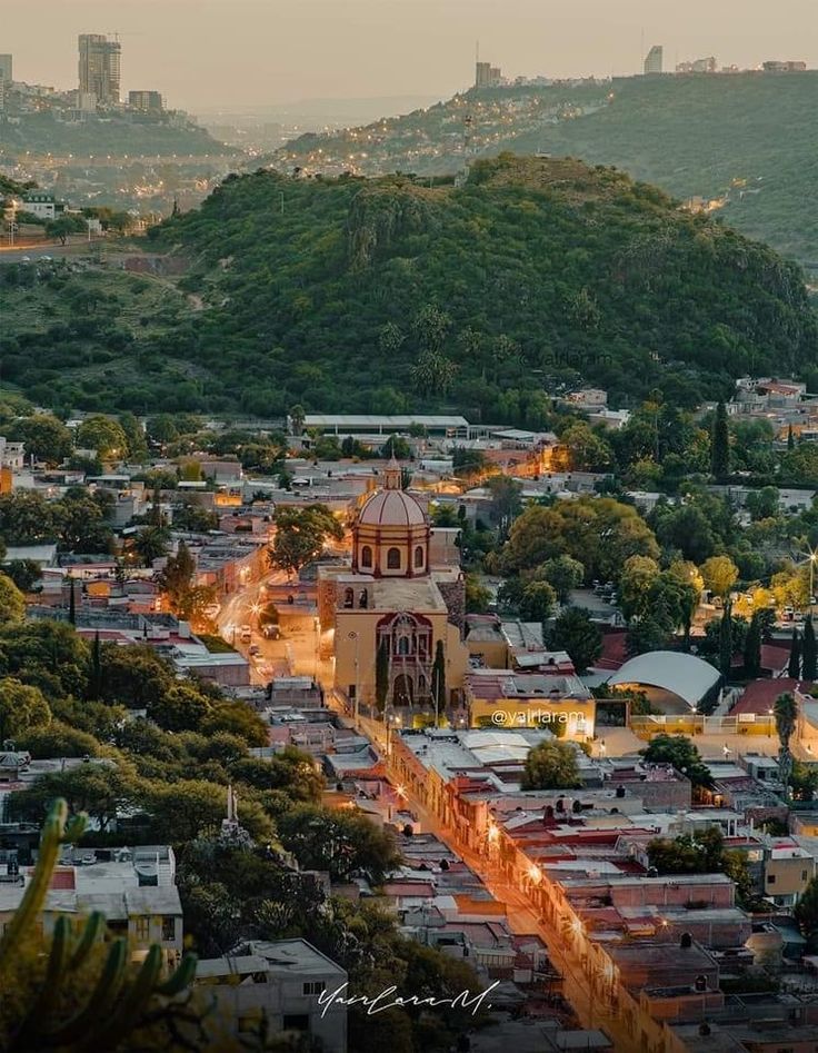 an aerial view of a city at dusk with mountains in the background