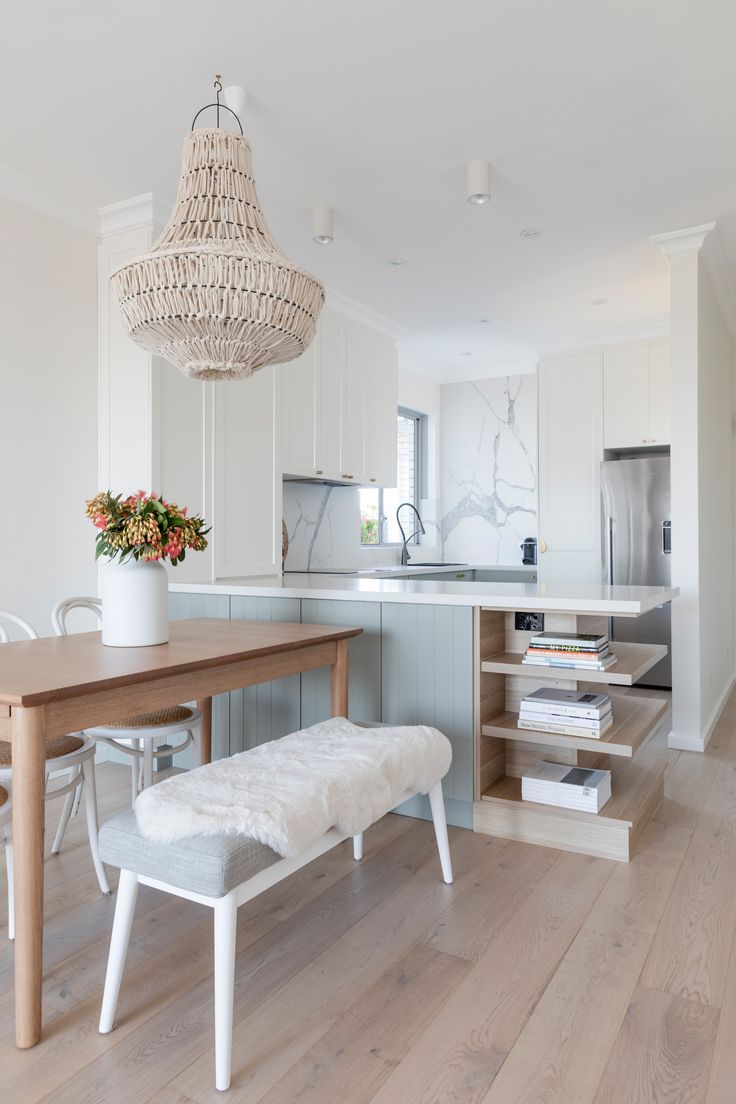 a dining room table and bench in a white kitchen with wood flooring on the side