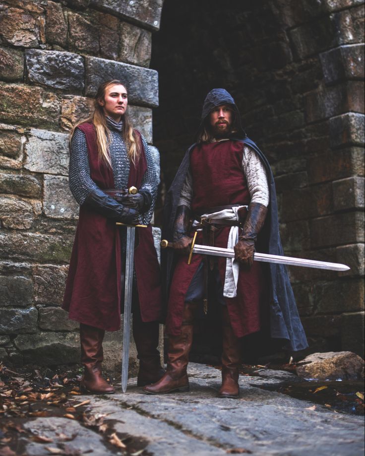 two people dressed in medieval clothing standing next to each other with swords and armor on