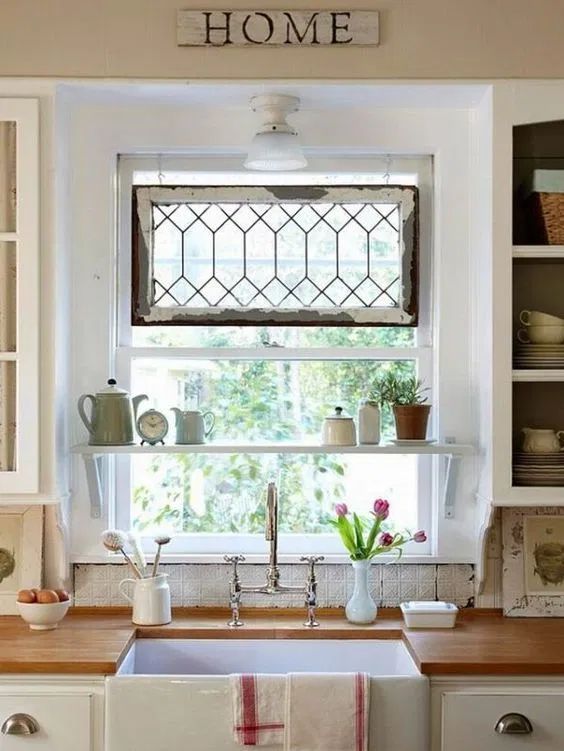 a kitchen sink sitting under a window next to a shelf filled with pots and pans