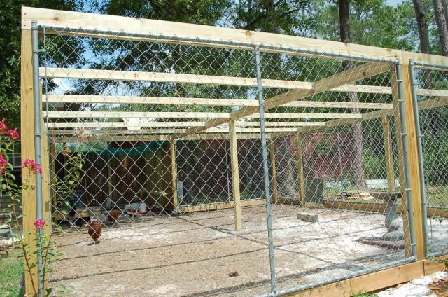 a chicken coop in the middle of a yard next to a fence with chickens inside