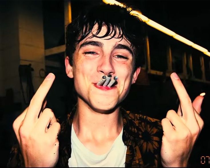 a young man is making the peace sign with his fingers while holding something in his mouth