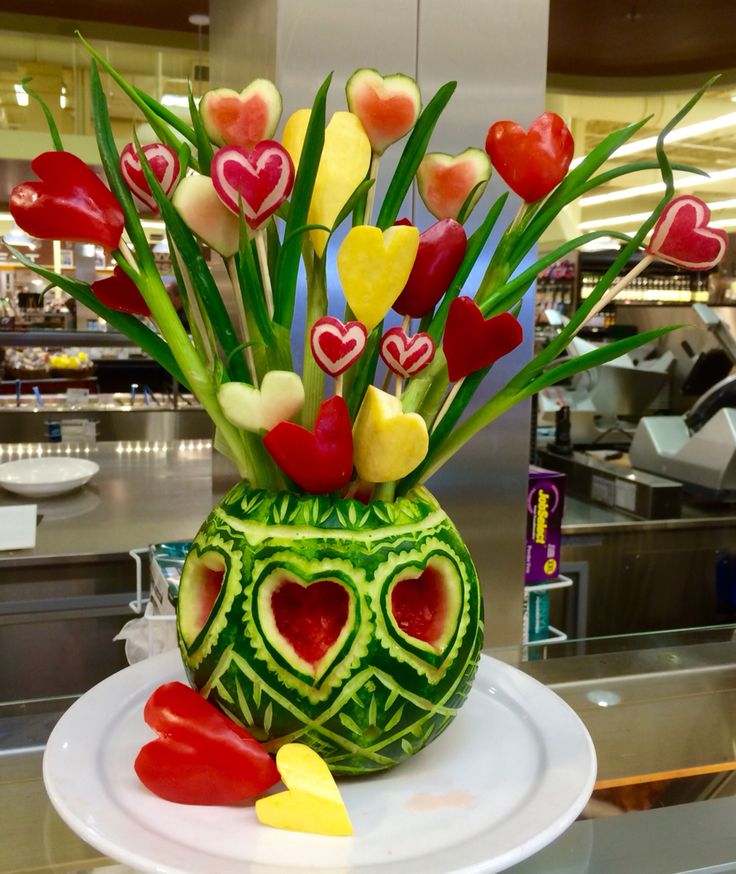 a watermelon sculpture with hearts and flowers in it