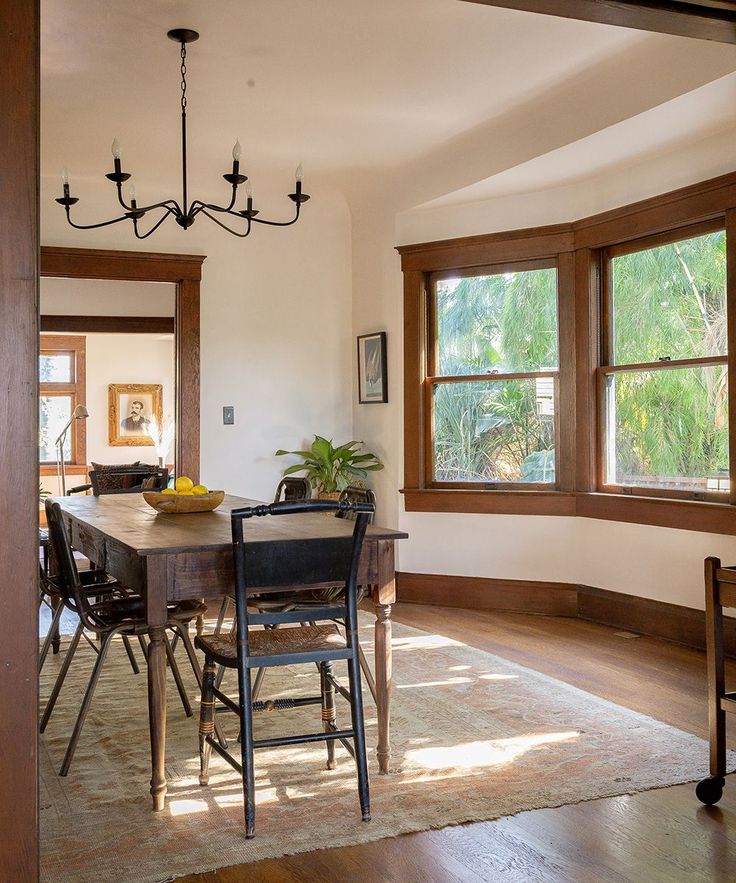 a dining room table and chairs in front of two windows with wood trimmings