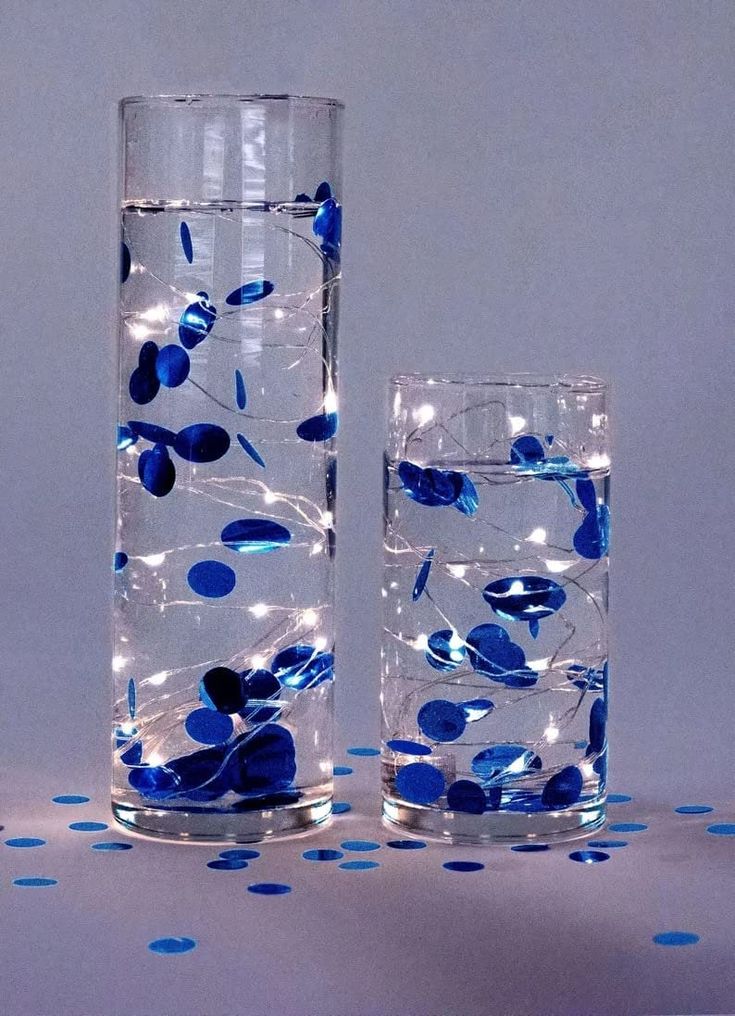 two tall vases with blue and white flowers in them, one is filled with water