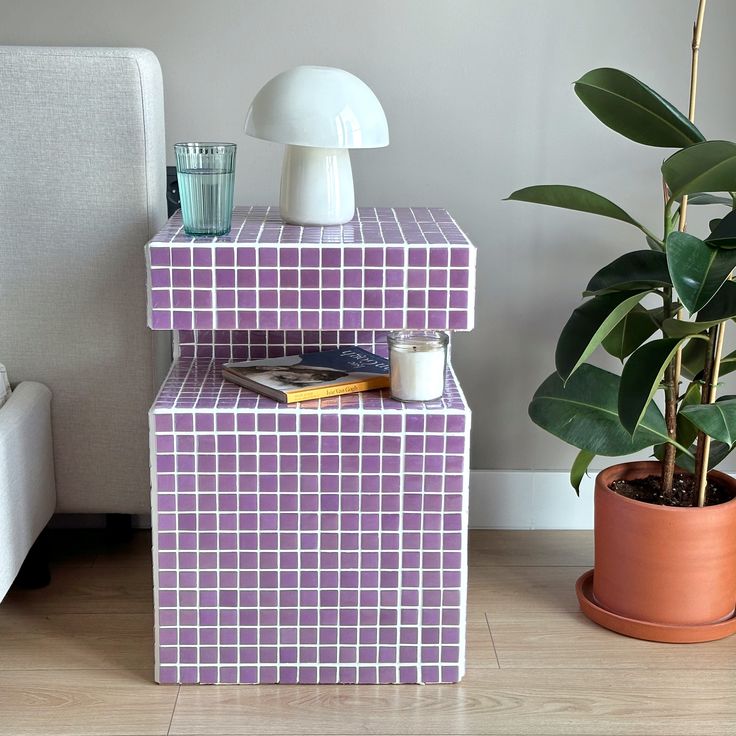 a potted plant sitting on top of a purple and white tiled shelf next to a couch