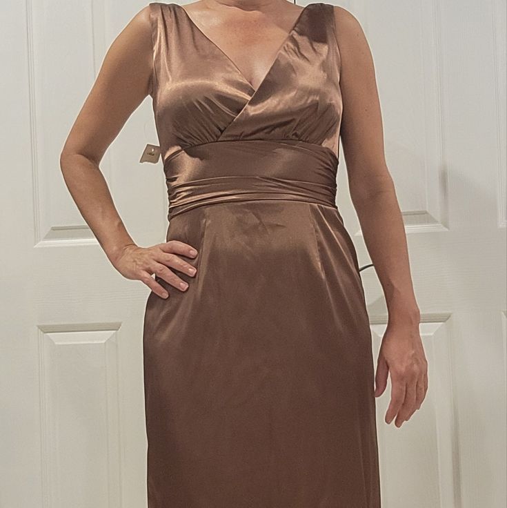 a woman wearing a brown dress standing in front of a door with her hands on her hips