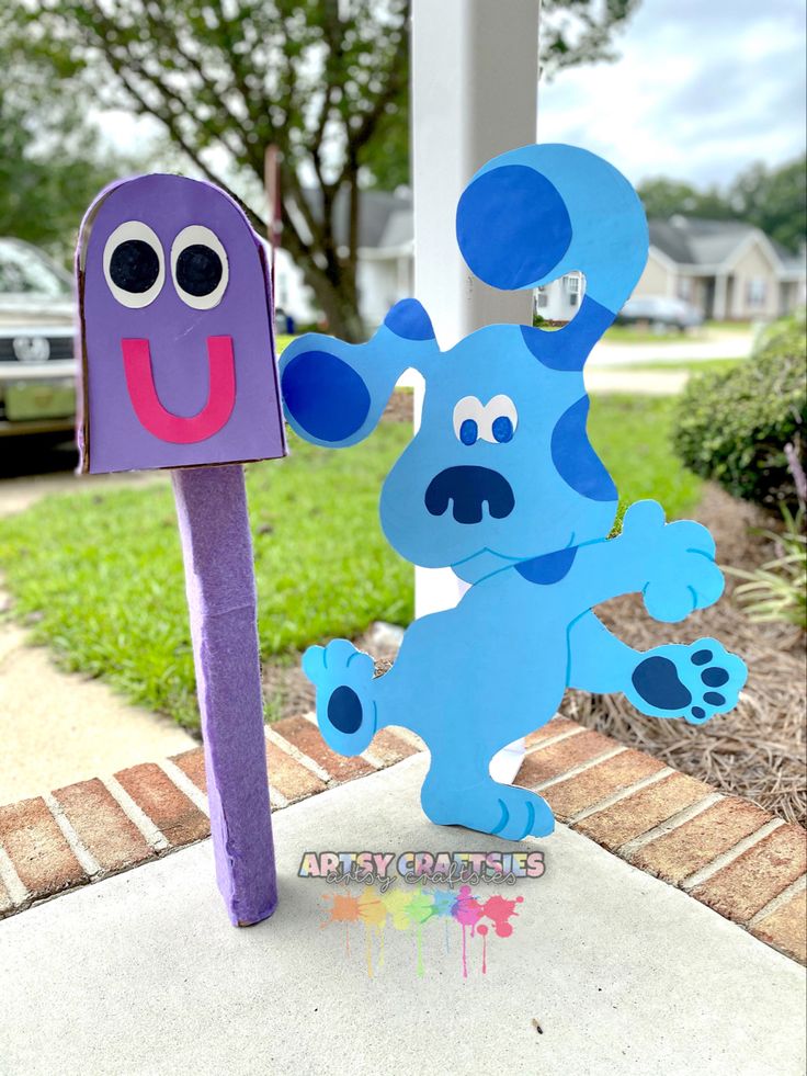 two paper cut out animals standing next to each other on a sidewalk with grass and trees in the background