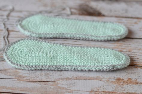 two crocheted green mittens sitting on top of a wooden table