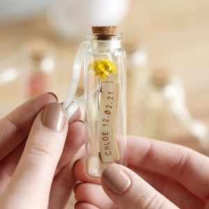 a person holding a tiny bottle with flowers in it