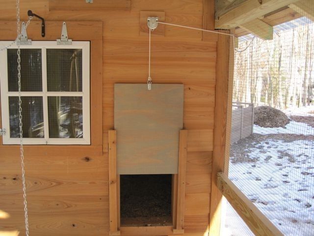 the inside of a small wooden house with a window and bird feeder hanging from it's side