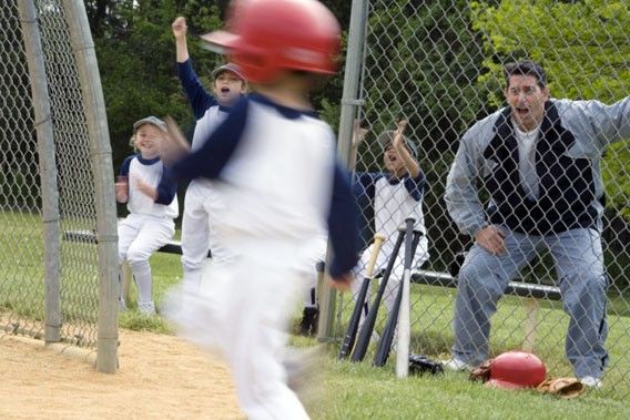 a group of kids playing baseball on a field with their hands up in the air