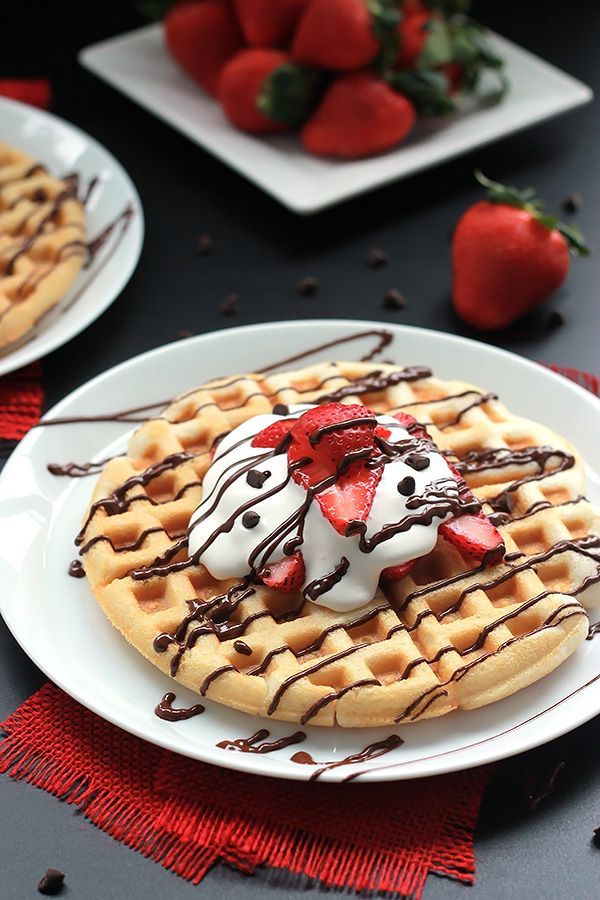 two waffles with strawberries and chocolate drizzled on them