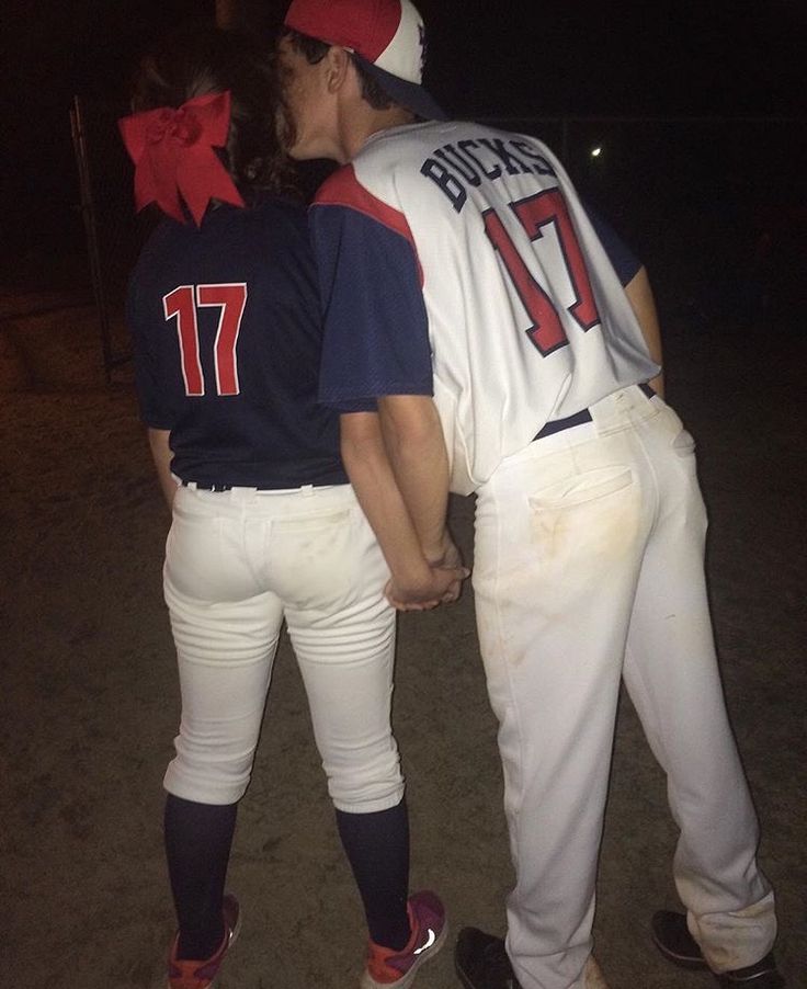 two baseball players standing next to each other on a field at night with one kissing the other's head