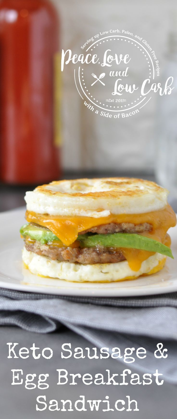 the keto sausage and egg breakfast sandwich is on a white plate next to a jar of ketchup