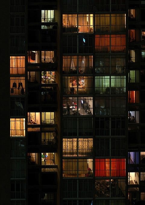 many windows are lit up at night in an office building's dark facade,