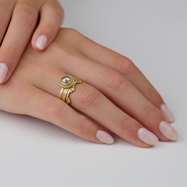 a woman's hand wearing a gold ring with an oval diamond and pearl on it