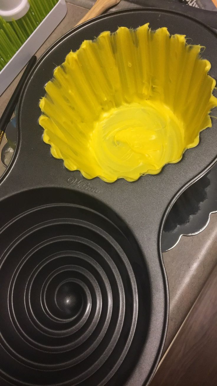 a cupcake pan with yellow icing in it